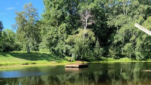 Ein sandiger Strand mit einem hölzernen Steg, der in einen ruhigen See führt, umgeben von dichtem Wald.