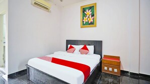 Een hotelkamer met een bed, nachtkastje, schilderij en een betegelde vloer.