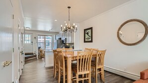 A dining area with a wooden table and chairs, a chandelier, and a large mirror on the wall. - 2-BD 3-BDR Ski Cabin (Silverthorne)