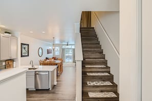 Uma cozinha moderna com uma escada de madeira que dá acesso a uma sala de jantar.