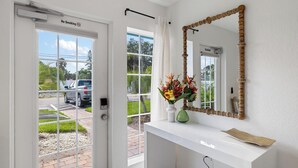 Um banheiro limpo e moderno, com um lavatório branco, um espelho com moldura de madeira e uma janela com vista para o exterior.