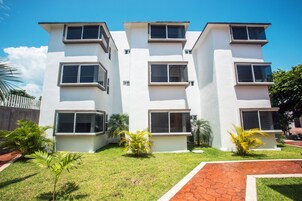 A multi-story residential building with balconies and a well-maintained lawn.
