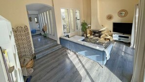 A spacious living area with a large window, a fireplace, and a television. - Architect-designed villa with swimming pool and large garden (Marseille)