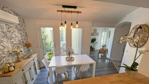 A modern kitchen with a white table, wooden cabinets, and a hanging light fixture. - Architect-designed villa with swimming pool and large garden (Marseille)