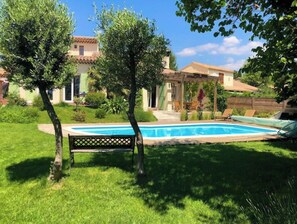 A backyard with a swimming pool, a pergola, and a bench.