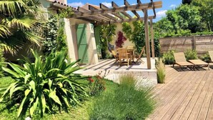 A wooden deck with a pergola, a table with chairs, and a garden with various plants. - Architect-designed villa with swimming pool and large garden (Marseille)