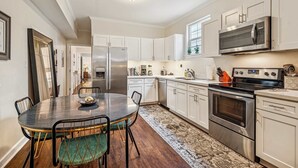 A modern kitchen with white cabinets, stainless steel appliances, and a dining area with a round table and chairs.