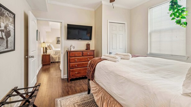 A bedroom with a bed, a dresser, a television, and a ceiling fan. - Stylish Condo w Sunny Backyard Patio 3br-2ba (New Orleans)