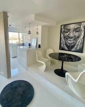 A modern kitchen with white cabinetry and a dining area featuring a marble table and white chairs. - 3 Pieces Arty au 14eme Étage Vue Panoramique ! (Créteil)