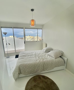 A modern bedroom with a large bed, a view of the city, and a unique ceiling light. - 3 Pieces Arty au 14eme Étage Vue Panoramique ! (Créteil)