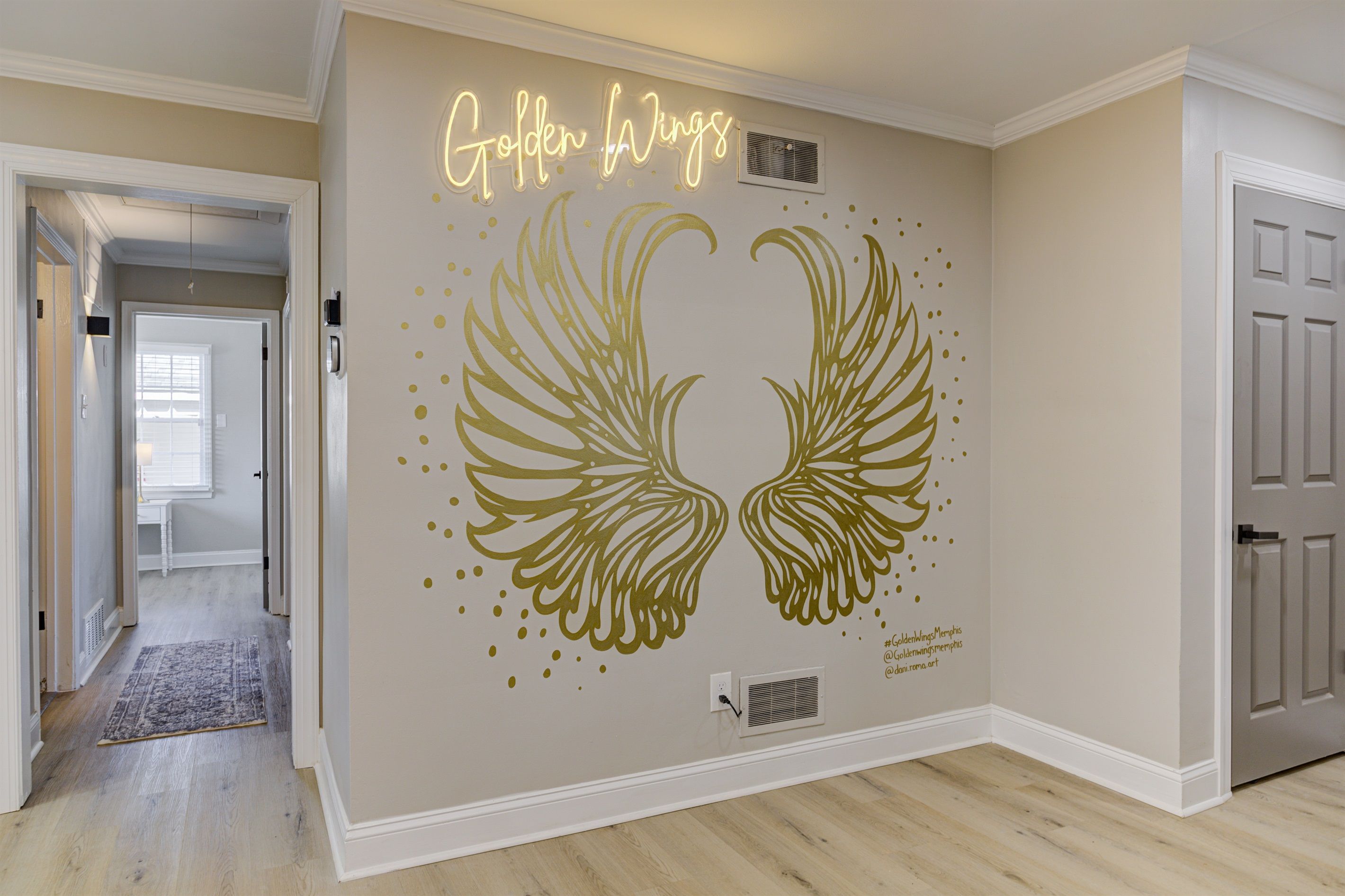 Een gang met een muur waarop een gouden vleugel sticker en de tekst 'Golden Wings' staat.