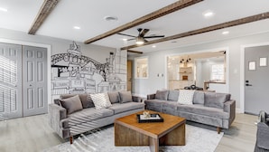 A modern living room with two grey sofas, a wooden coffee table, and a cityscape mural on the wall.