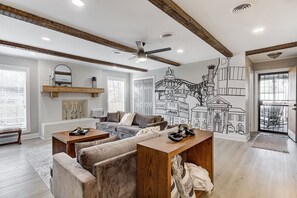 A spacious living room with a large sectional sofa, wooden coffee table, and a mural of a cityscape on the wall.