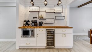 A modern kitchen with white cabinetry, a wooden countertop, built-in appliances, and decorative lighting.
