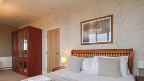 Ett hotellrum med en stor säng, en garderob i trä, en dörr och en inramad tavla på väggen.