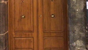 A wooden double door with a number plaque, set in a stone archway. - Base Napoli Plebiscito (Naples)