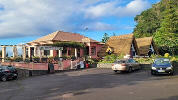 Ein Restaurant mit roter Fassade und einem Strohdach, umgeben von üppigem Grün.