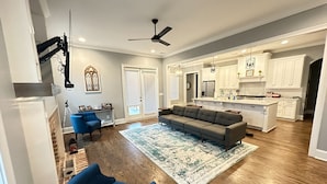 A spacious living room with a large sectional sofa, a blue armchair, and a patterned rug. - Beautiful Masters Rental Quiet Neighborhood (EVANS)