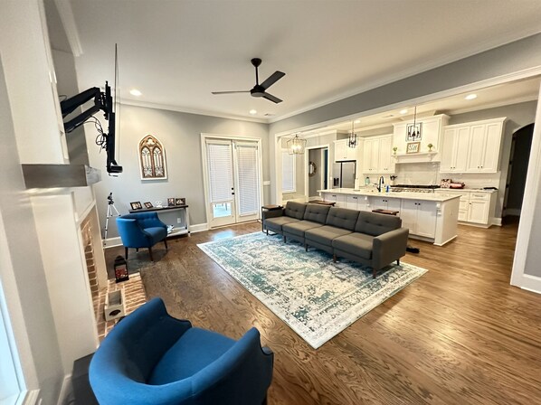 A spacious living room with a large sectional sofa, a blue armchair, and a patterned rug.