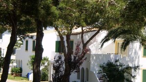 Un bâtiment blanc avec des volets verts et un escalier menant à un étage supérieur.