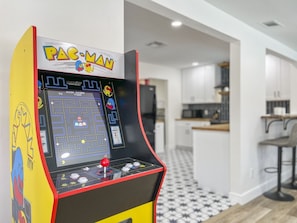 A Pac-Man arcade machine in a modern kitchen with a black and white patterned floor.