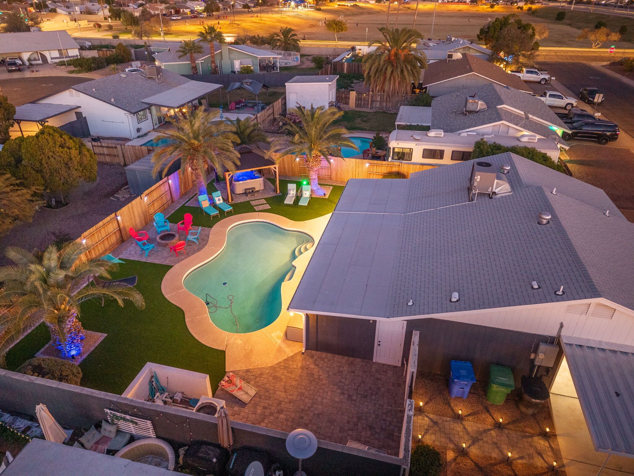A residential area with a swimming pool, palm trees, and houses.