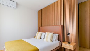 A modern bedroom with a bed, bedside table, and a wall-mounted air conditioner. -  2BR Chic&Bright com 120m2 em Campo de Ourique (Lisbon)