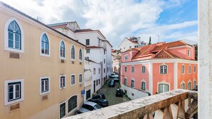 A narrow street with buildings on either side, a cobblestone road, and a stone balustrade. -  2BR Chic&Bright com 120m2 em Campo de Ourique (Lisbon)