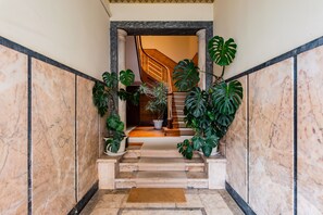A marble staircase with a wooden handrail, leading to a landing with a potted plant. -  2BR Chic&Bright com 120m2 em Campo de Ourique (Lisbon)