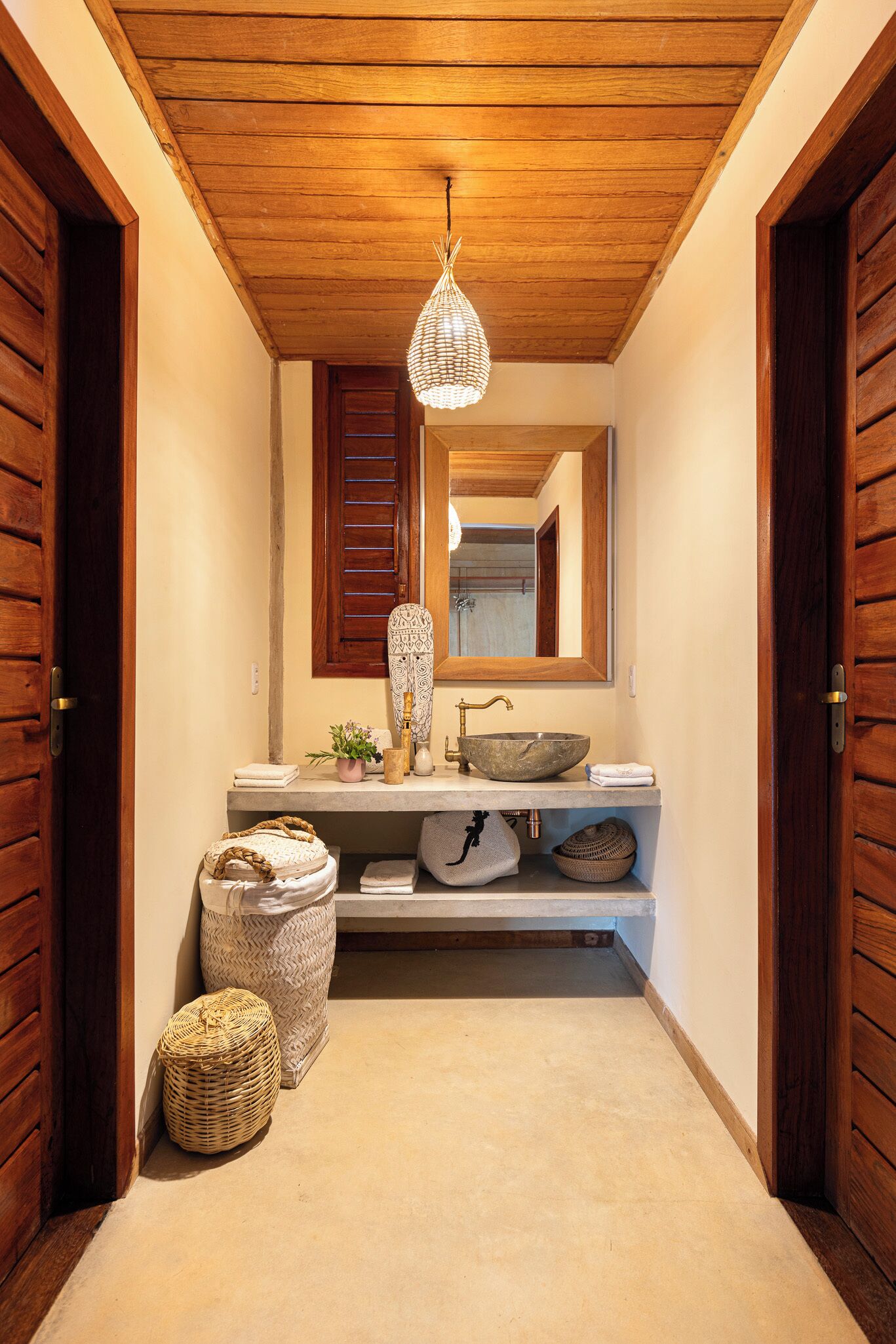 A narrow hallway with a wooden ceiling, a stone sink, and a mirror above it.