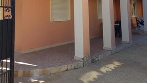 Un bâtiment à deux étages, doté d’une façade de couleur pêche, d’un portail noir et d’un patio couvert agrémenté d’arcades.