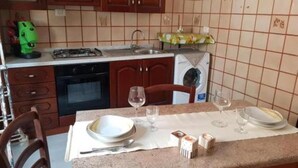 Une cuisine équipée d’une cuisinière, d’un four et d’un évier. On y trouve une table à manger avec des assiettes et des verres.