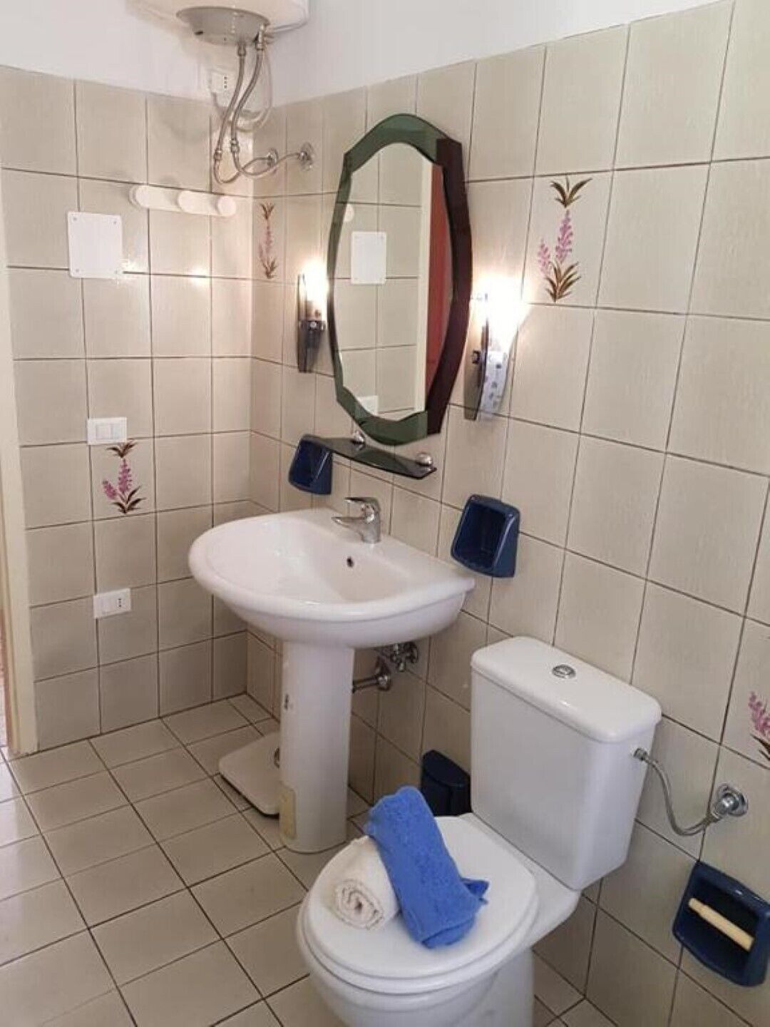 Un bagno con lavandino, WC e doccia, tutti in bianco.