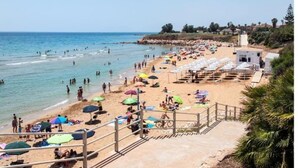 Une plage avec des parasols, des chaises longues et une tour de surveillance pour les sauveteurs.