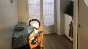 Un pequeño comedor con una mesa y sillas, un ventilador de techo y vistas a un espacio exterior a través de un ventanal.