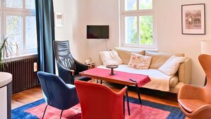 A cozy living room with a sofa, two chairs, a coffee table, a TV, and a window with a view of trees. - VILLA FOREST & LAKES near Berlin - Country villa with horses, fireplace & peace! (Marienwerder-Ruhlsdorf)