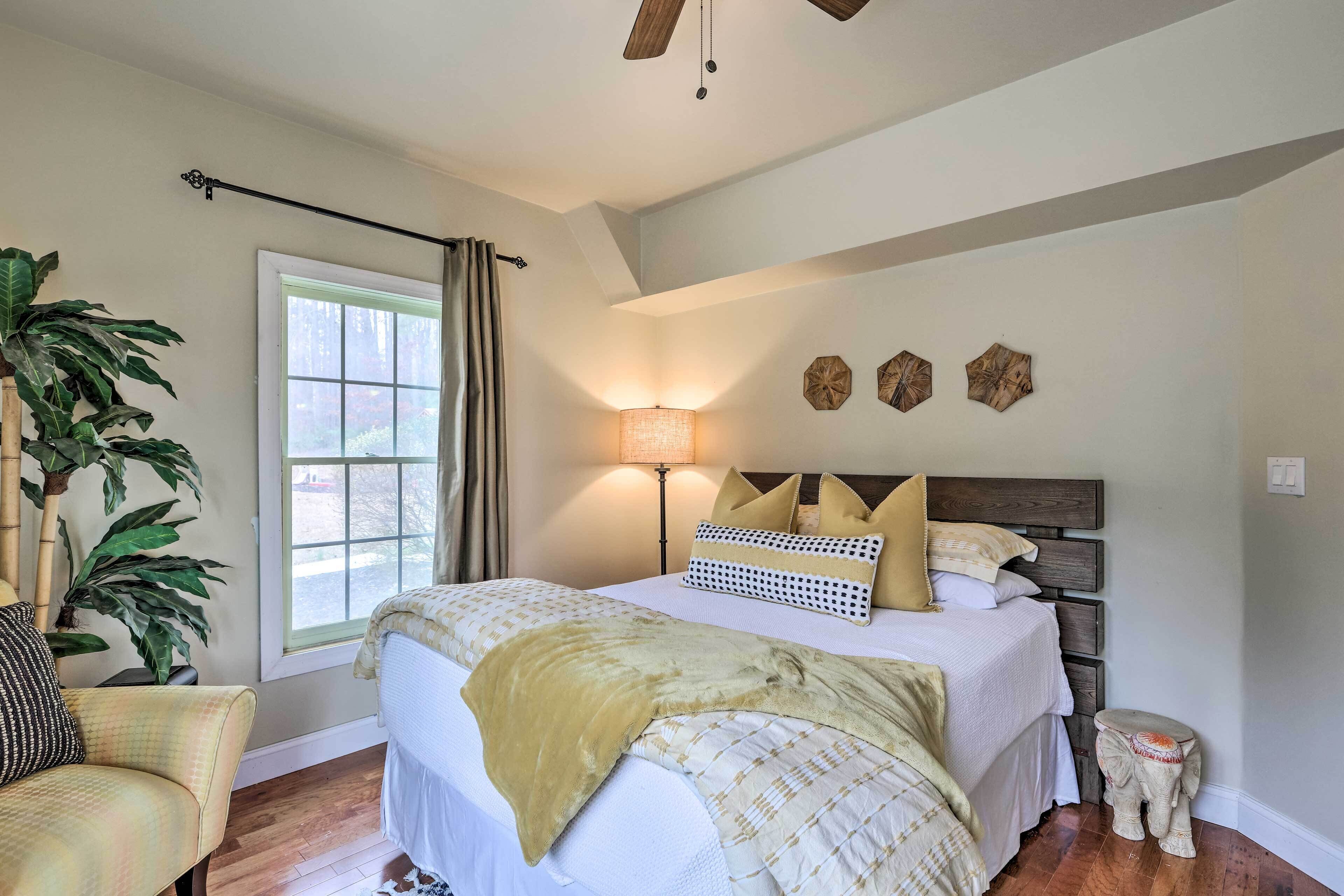 A bedroom with a bed, bedside lamp, decorative wall art, and a potted plant.