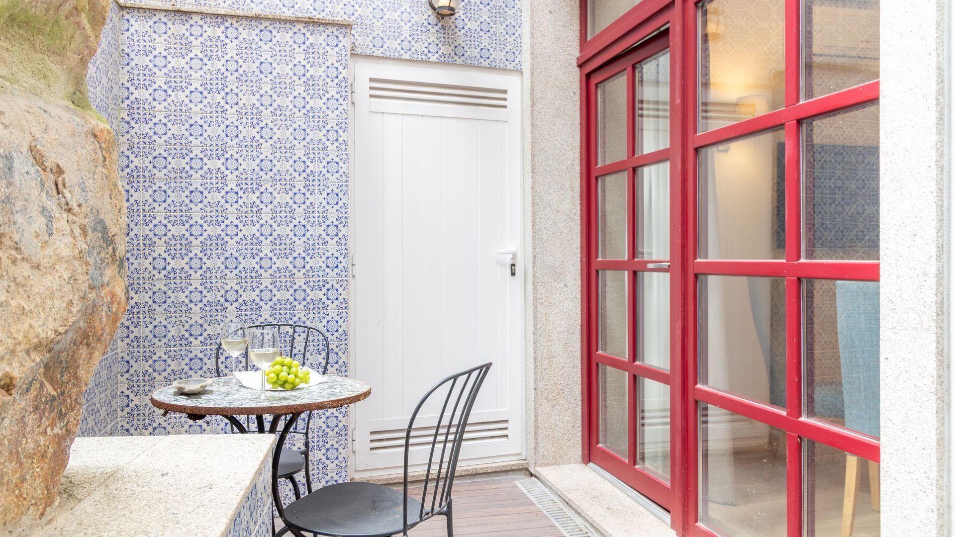 A small patio with a table, chairs, and a glass of white wine.