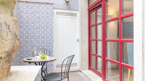 A small patio with a table, chairs, and a glass of white wine.