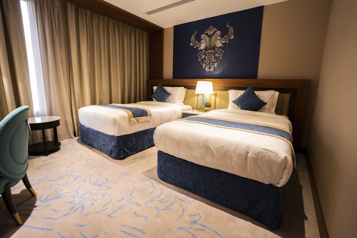 A hotel room with two beds, a desk, and a chair.