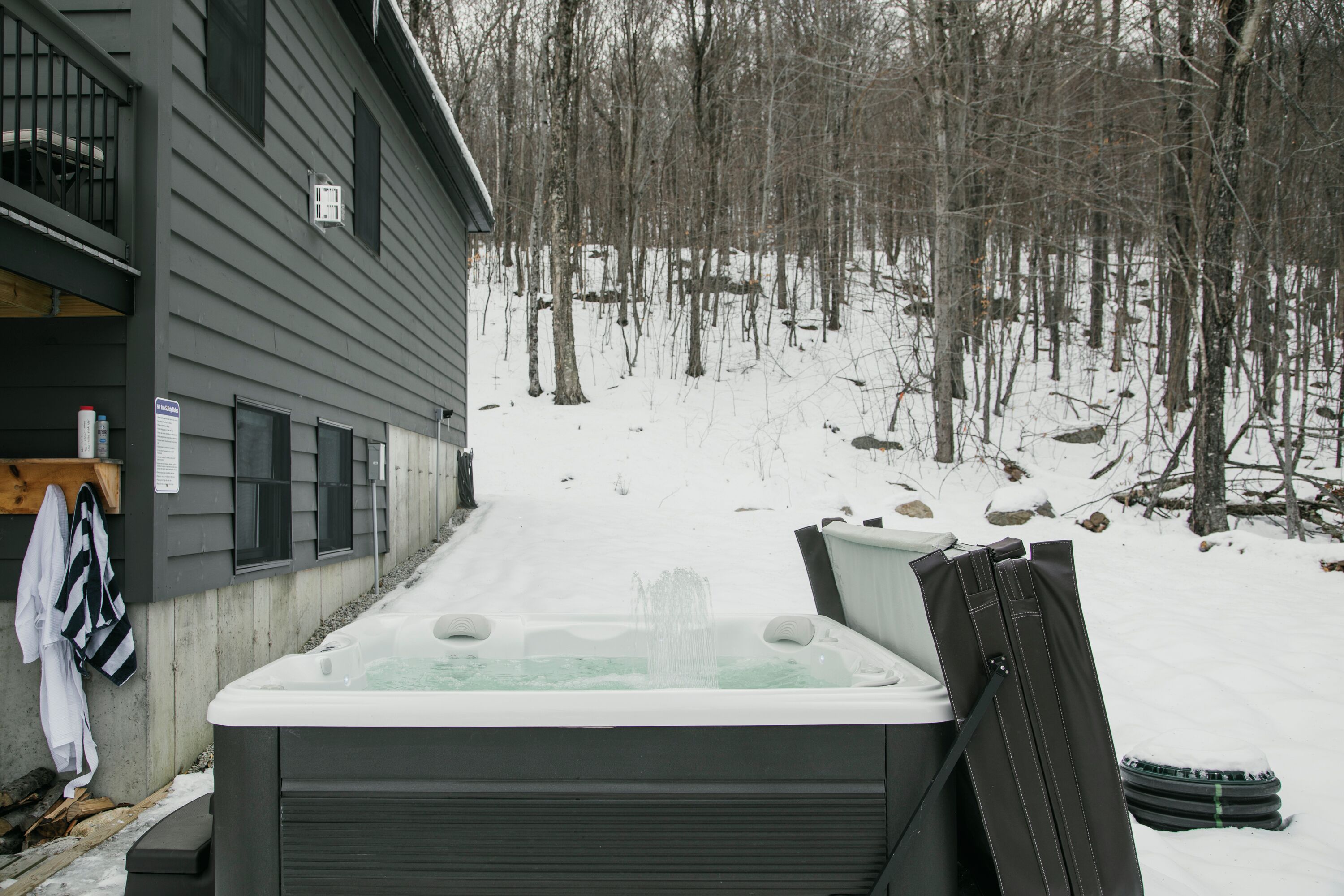 Un bain à remous dans un décor extérieur enneigé, avec une maison en arrière-plan.