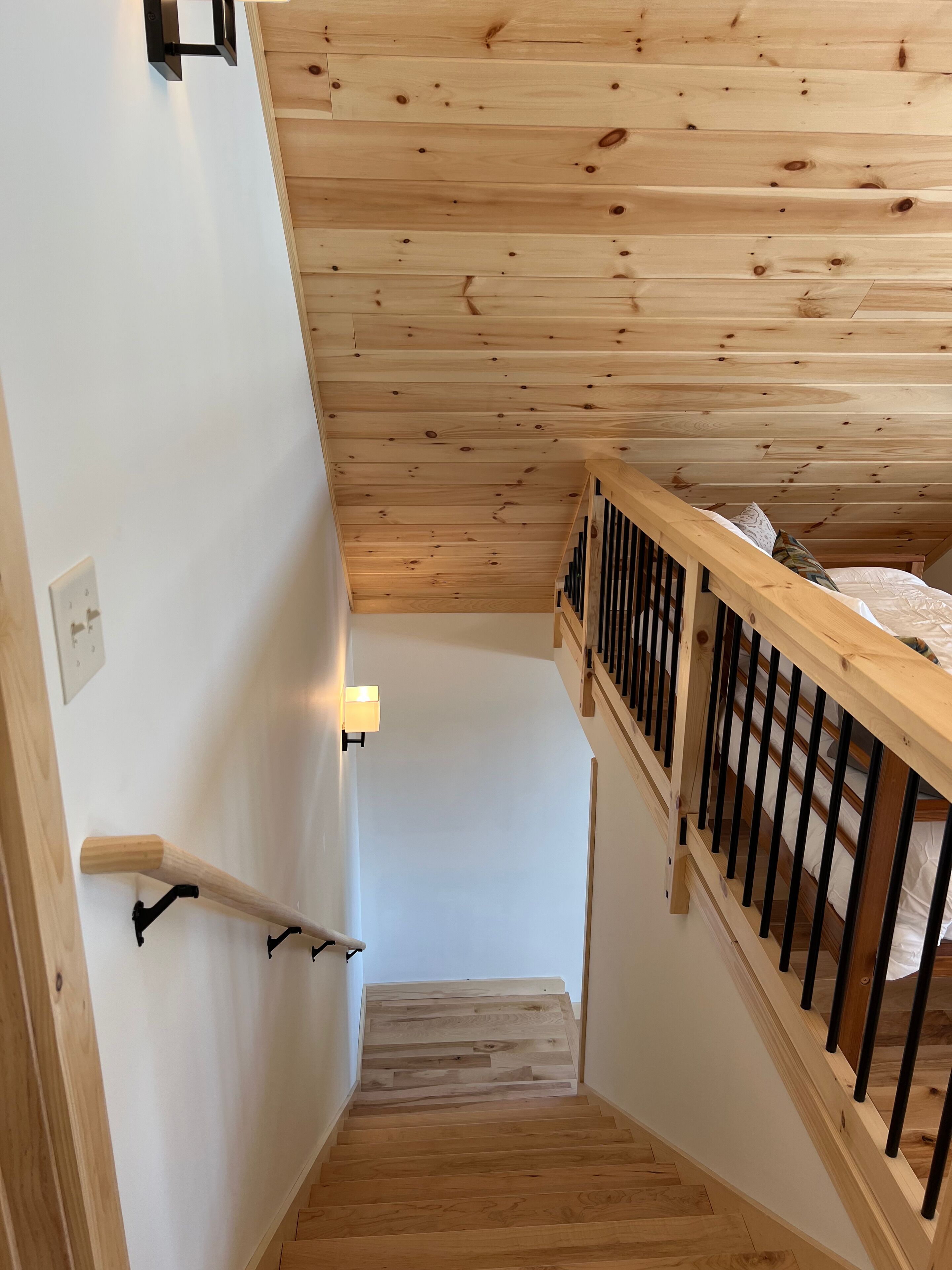 A wooden staircase with a white wall and a wooden railing.