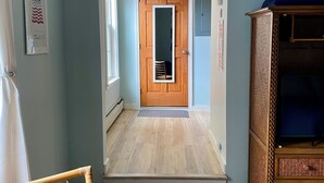 Une pièce avec une porte en bois, un miroir, un petit tapis et une armoire en bois.