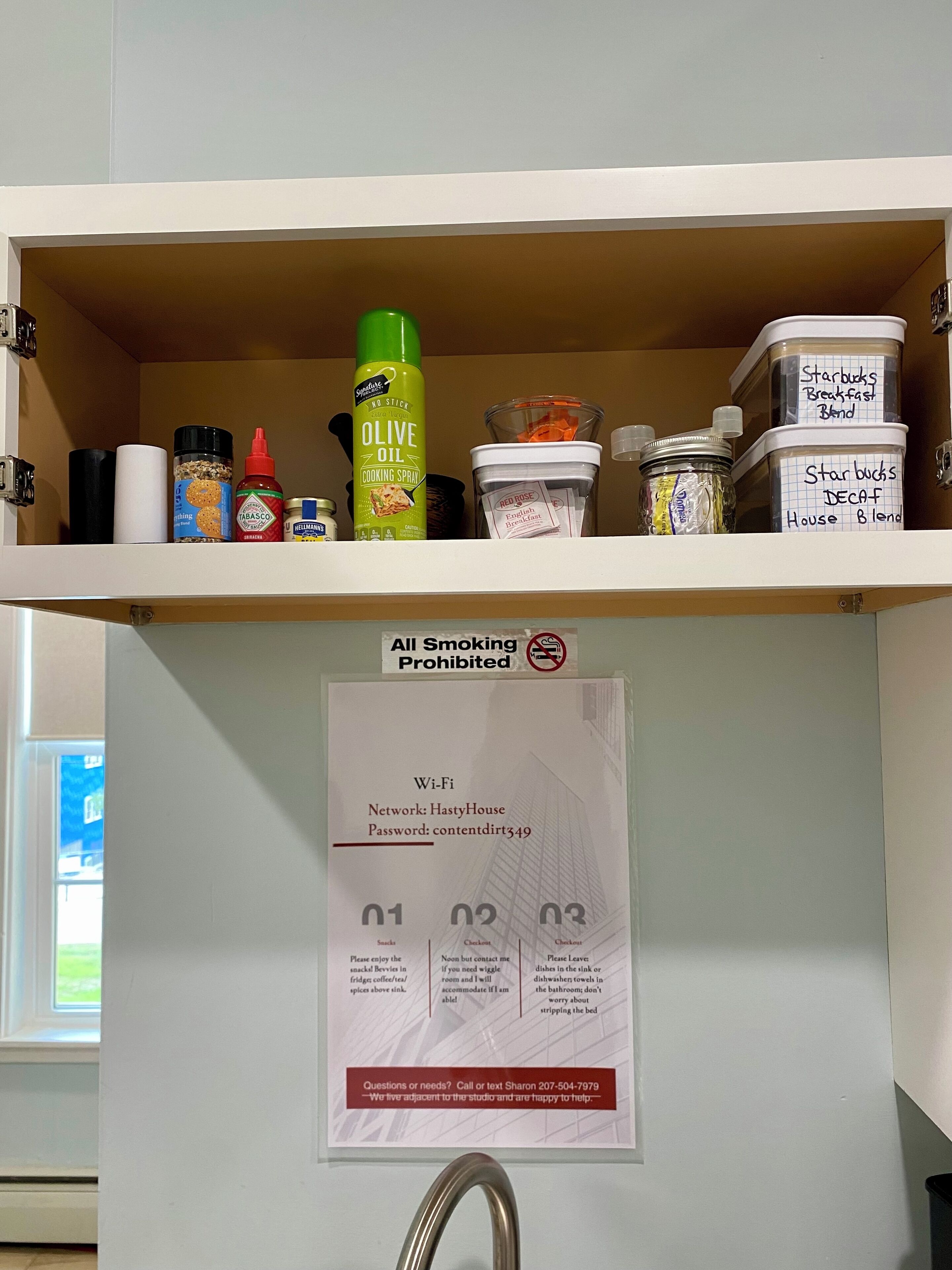Een keukenkastje met diverse spullen, waaronder kookspray, kruiden en gemarkeerde containers voor koffiemelanges.