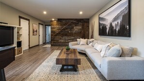 Un salon moderne avec un escalier en bois, un grand canapé, une table basse et un téléviseur.