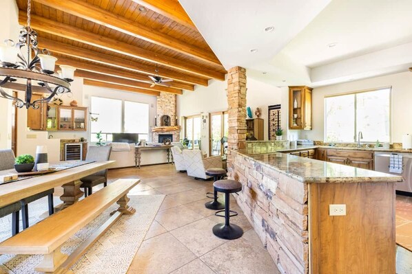A spacious kitchen with a stone accent wall, wooden beams, and a bar area with stools.
