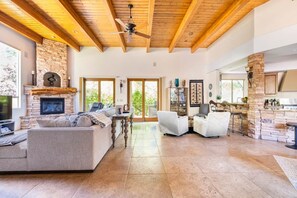 A spacious living area with a stone fireplace, a ceiling fan, and a large window.