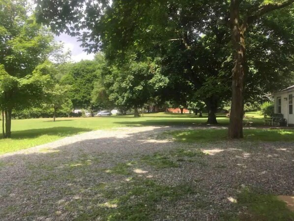 A gravel path leading through a park with trees and a building in the background.