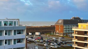 Une vue sur la côte, avec un parking, des bâtiments et la mer.