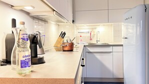 Une cuisine moderne avec des armoires blanches, des appareils en acier inoxydable et un plan de travail en bois.